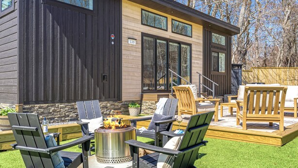 Una casa moderna con terraza, mobiliario exterior y una fogata.