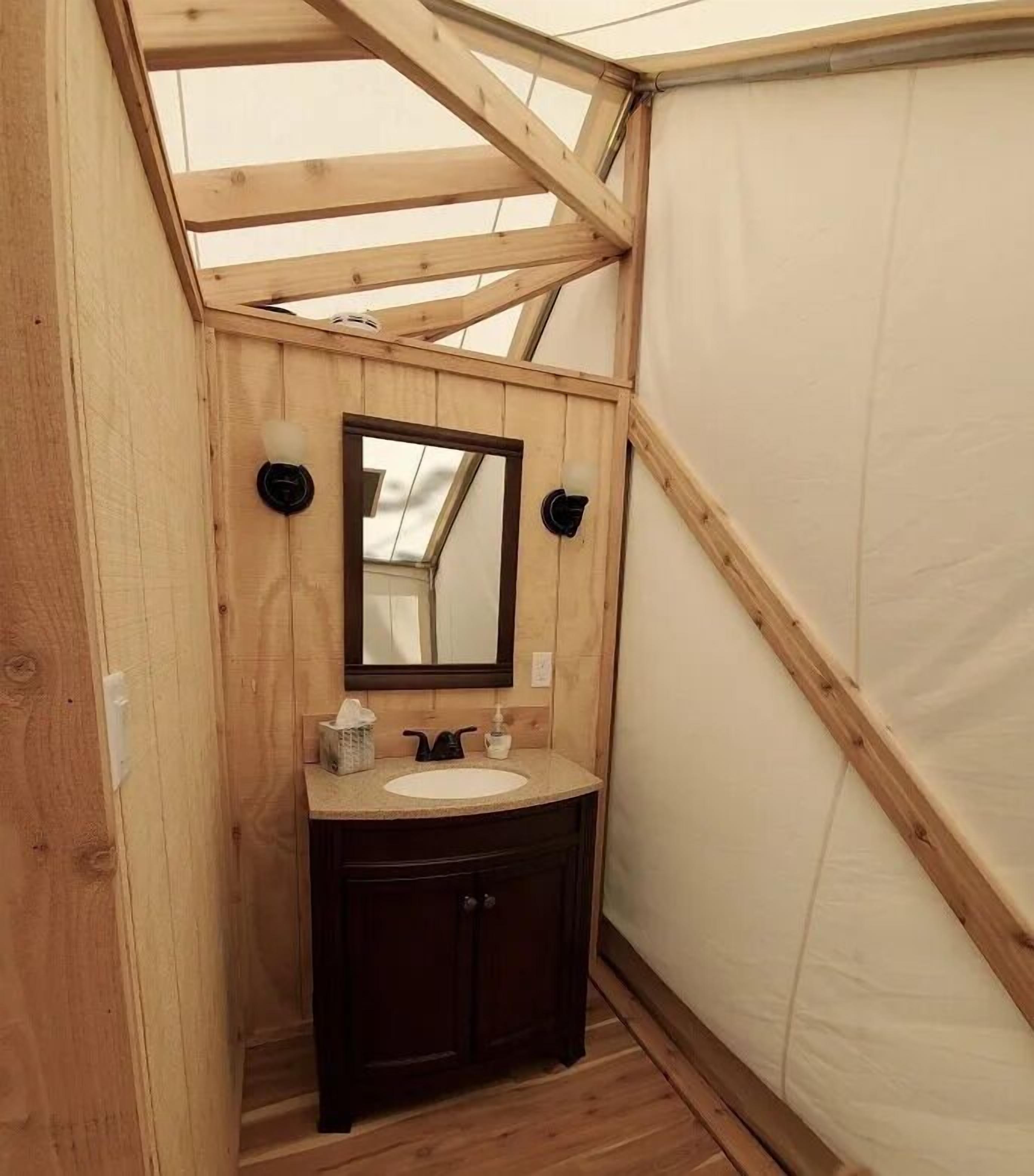 Un baño pequeño de madera con un lavabo, muebles oscuros y un espejo.