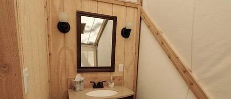 Un baño pequeño de madera con un lavabo, muebles oscuros y un espejo.