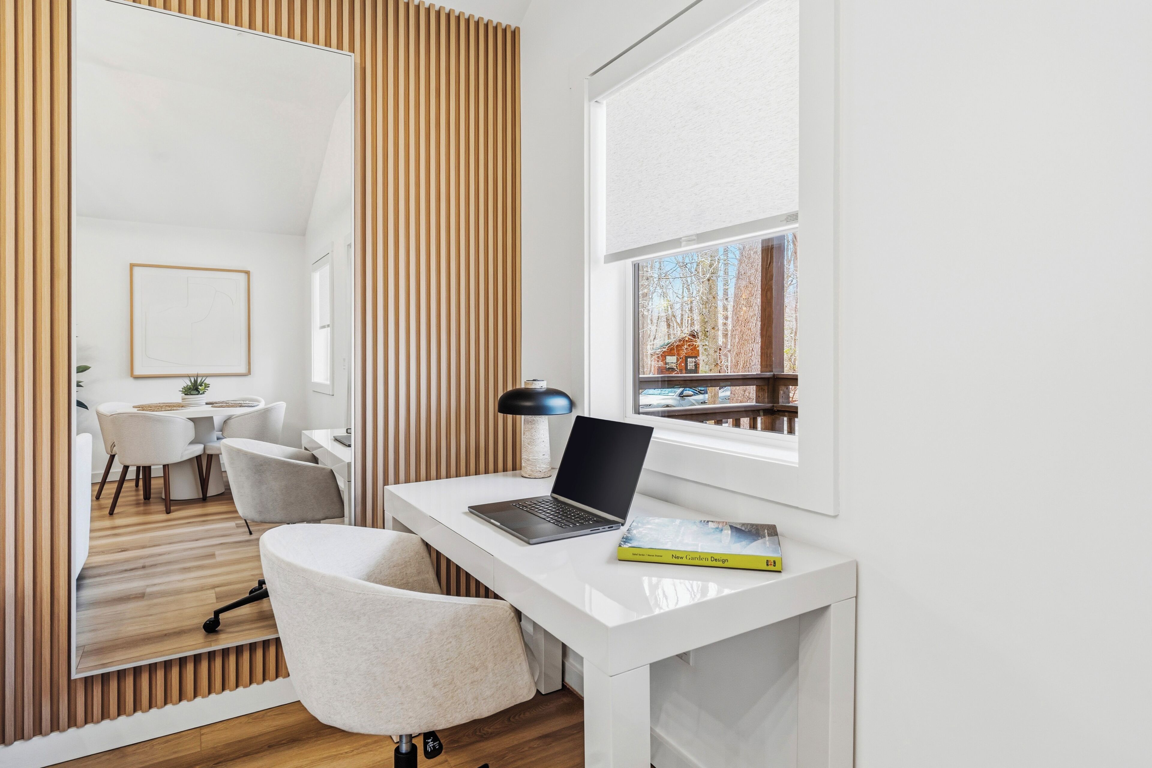 A modern office space with a white desk, a laptop, a lamp, and a book.
