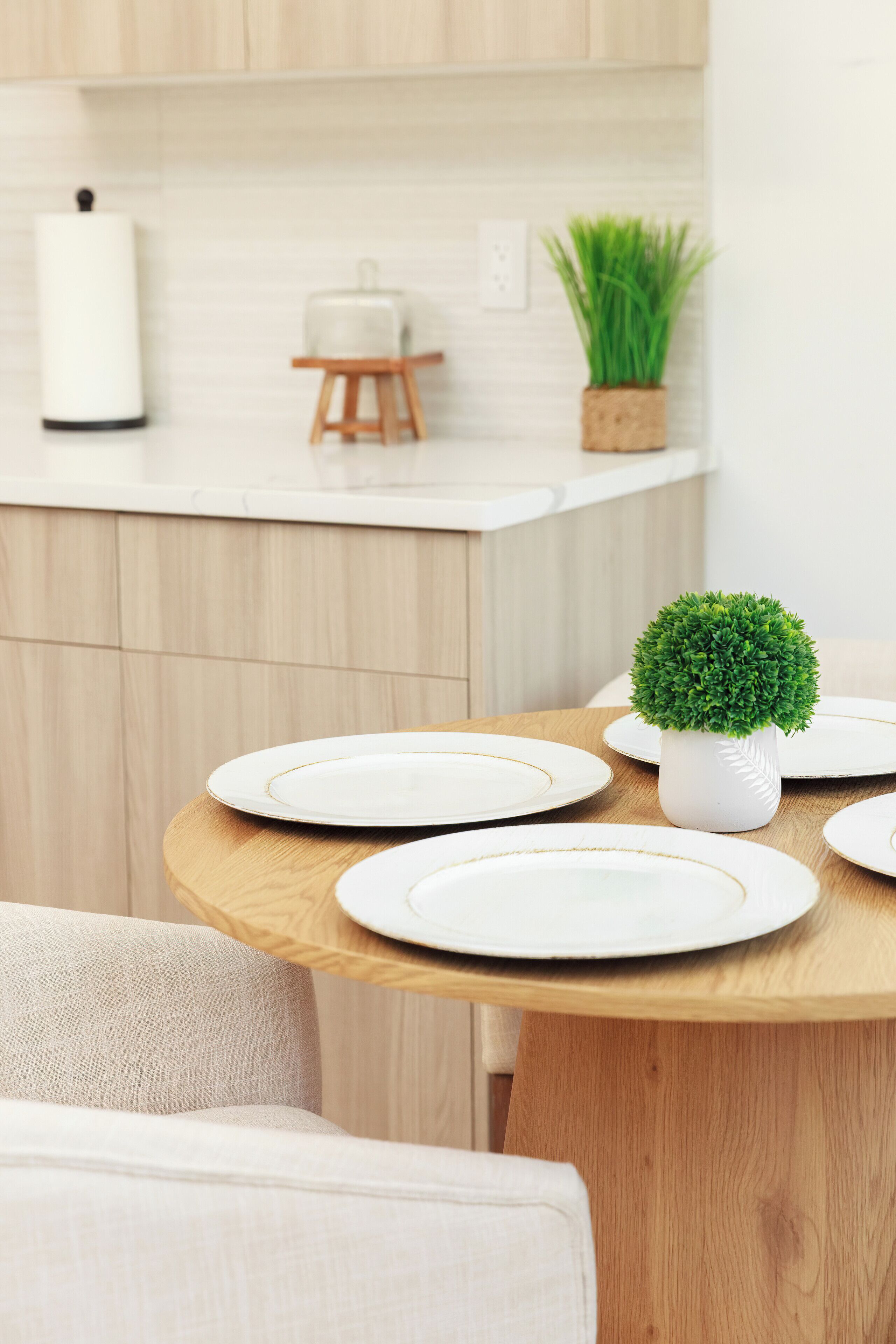 Een eettafel met witte borden en een kleine potplant.
