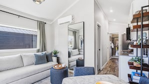 Una sala de estar moderna con sofá, mesa de comedor y zona de cocina al fondo.