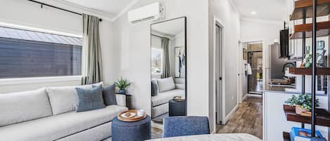 A modern living room with a sofa, a dining table, and a kitchen area in the background.