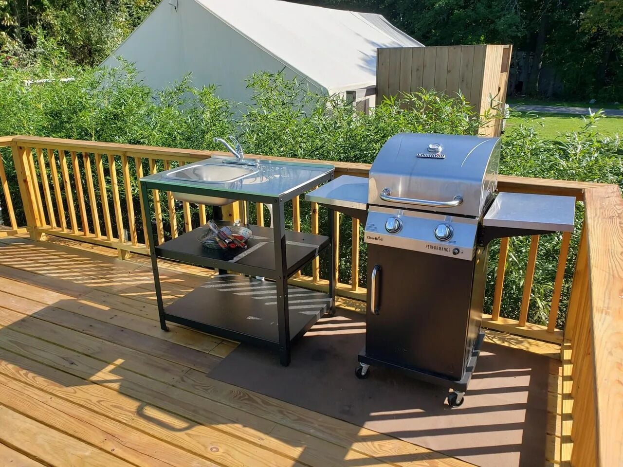 A wooden deck with a glass-top table and a portable grill.