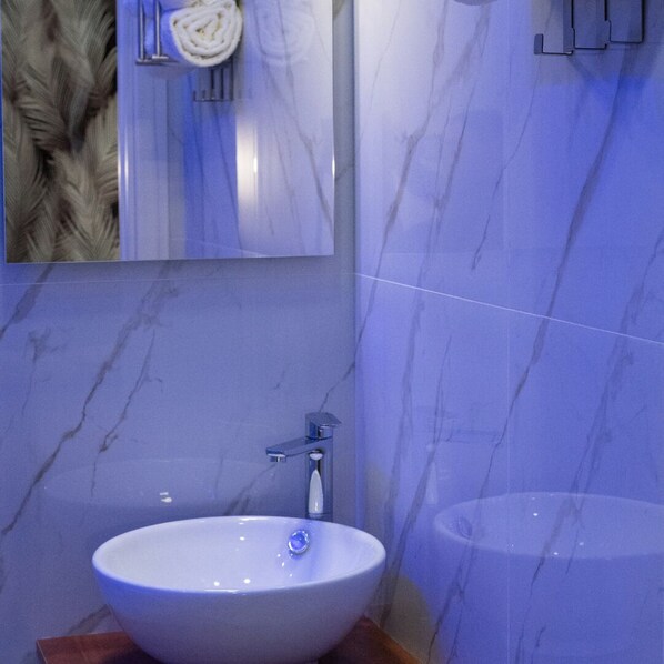A bathroom with a white sink, a mirror, and a towel hanging on the wall. - Stella Mia Luxury Rooms (Naples)