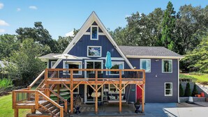 A two-story house with a wooden deck, a covered patio, and a front door. - Lake house views, w/dock in quiet cove, new renovations & great outdoors spaces! (Dahlonega)