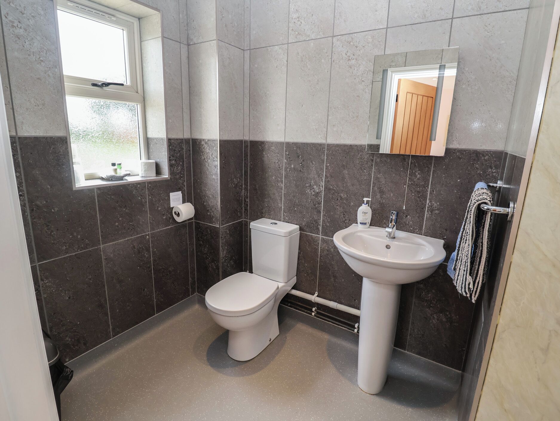 A bathroom with a toilet, sink, and window.