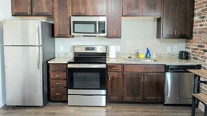 A kitchen with dark wooden cabinets, stainless steel appliances, and a granite countertop.