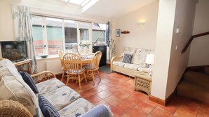 A cozy living room with a dining area, a sofa, a TV, and a window with curtains. - Churn House (Ipswich)
