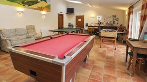 A pool table in a room with a sofa, a painting, and a table with a foosball table. - Churn House (Ipswich)