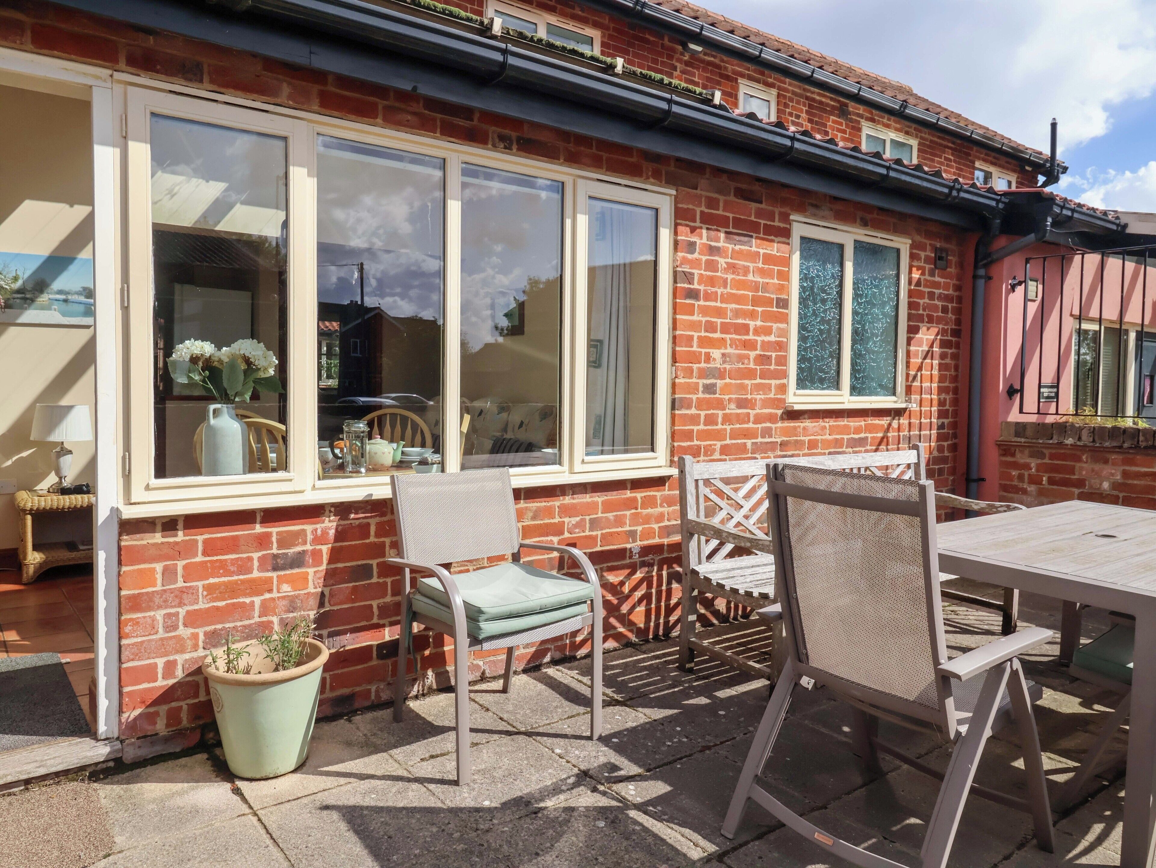 A patio with a table and chairs, a potted plant, and a window with a view of the street.