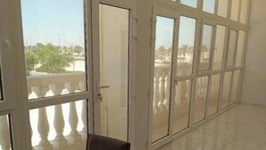 A room with a large window, a wooden table, and two chairs.