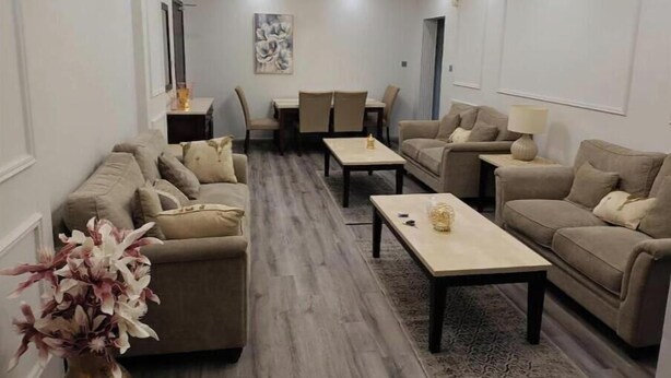 A modern living room with a sofa set, a coffee table, and a dining area with chairs and a table.