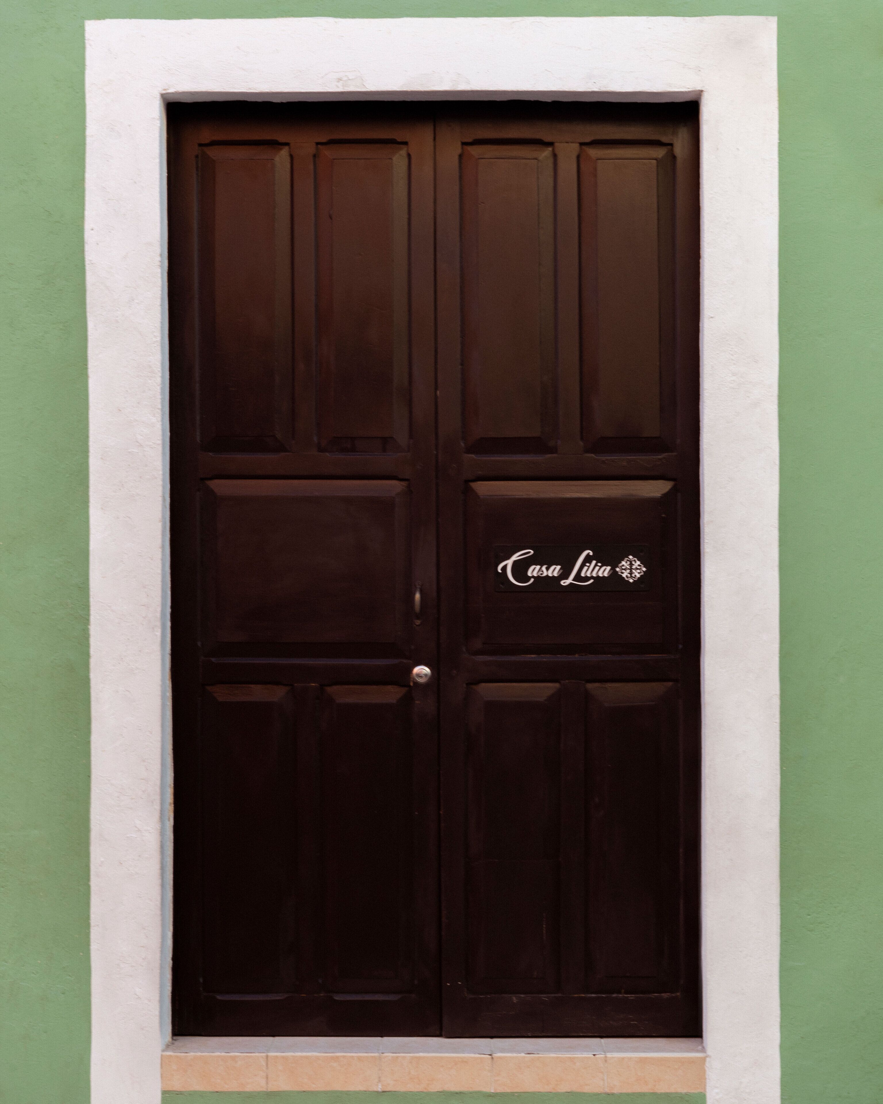 A dark brown double door with a sign that reads "Casa Linda."