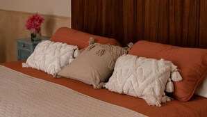 A bed with a wooden headboard, two pillows, and a vase with flowers on a nightstand. - Renovated colonial house in Campeche's historic center (San Francisco de Campeche)