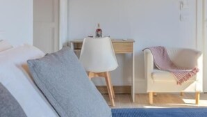 A modern bedroom with a wooden ceiling, a white bed, a desk, and a chair.