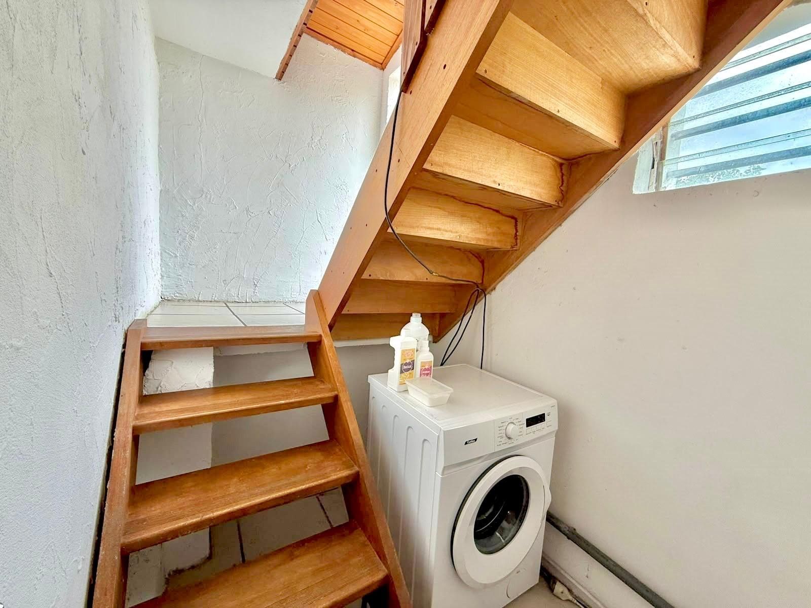 Un área de lavandería con lavadora y una escalera de madera.