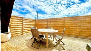 Eine Holzterrasse mit einem runden Tisch und Stühlen, umgeben von einem Holzzaun.