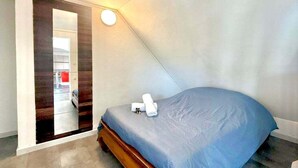 Un dormitorio con cama, espejo y lámpara.