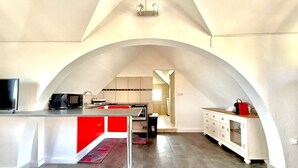 Una cocina moderna con una isla central, armarios blancos y una pared de acento roja.