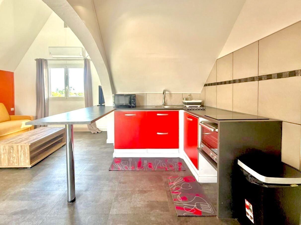 A modern kitchen with red cabinets, a black countertop, and a built-in stove.