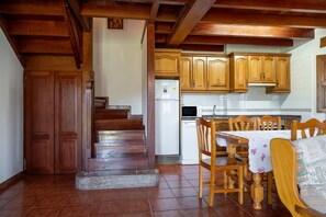 Una cocina con armarios de madera, una mesa de comedor con sillas y un refrigerador.