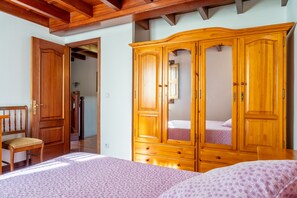 Een slaapkamer met een houten garderobe, een bed, een stoel en een houten plafond.