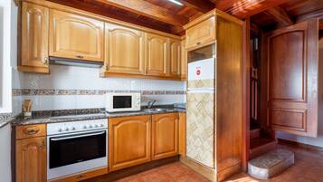 Una cocina con armarios de madera, un microondas, un horno y un refrigerador.