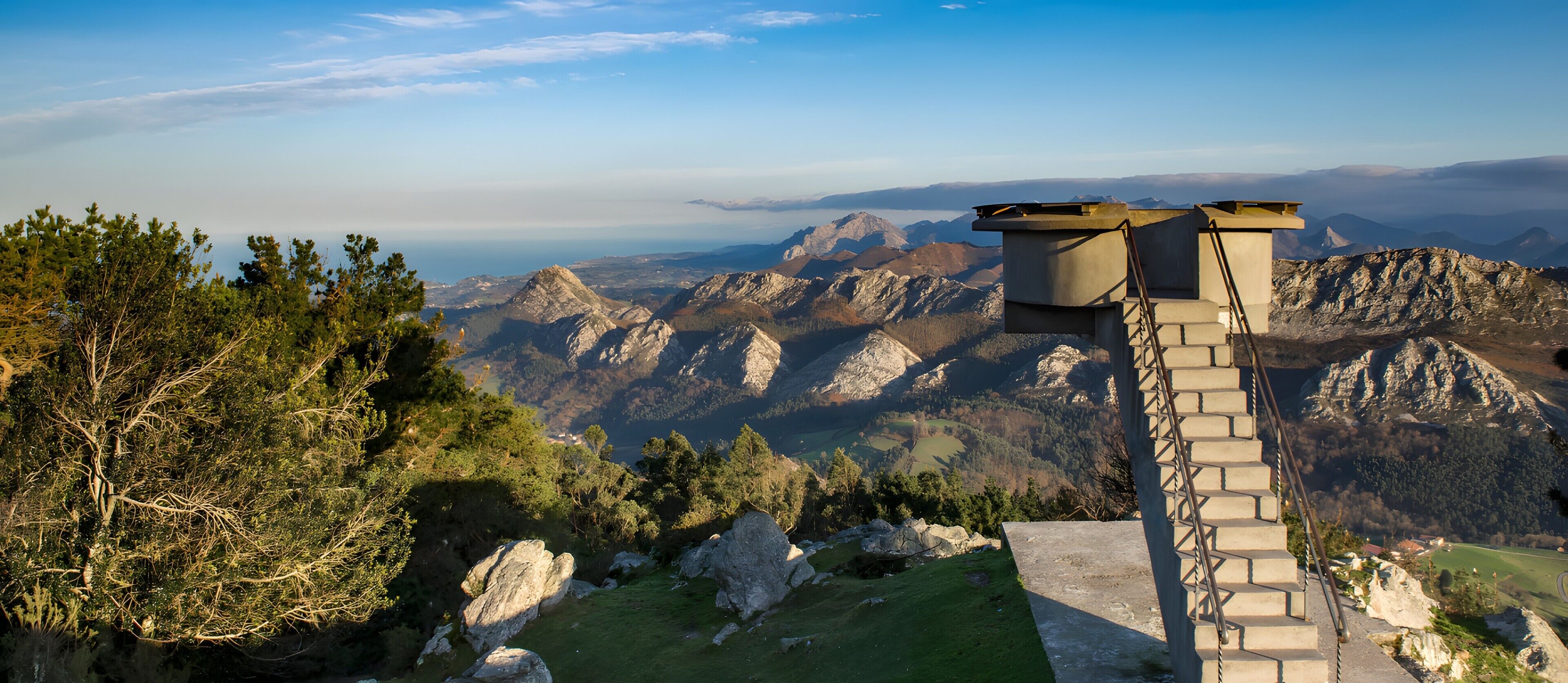 Una scala in pietra conduce a una terrazza panoramica con vista sulle montagne.