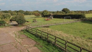 A rural park with picnic tables, a small wooden structure, and a fenced area. - Wheelwright's Cottage (Ipswich)