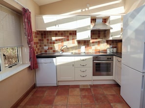A compact kitchen with white cabinets, a Bosch dishwasher, a stove, and a refrigerator. - Wheelwright's Cottage (Ipswich)