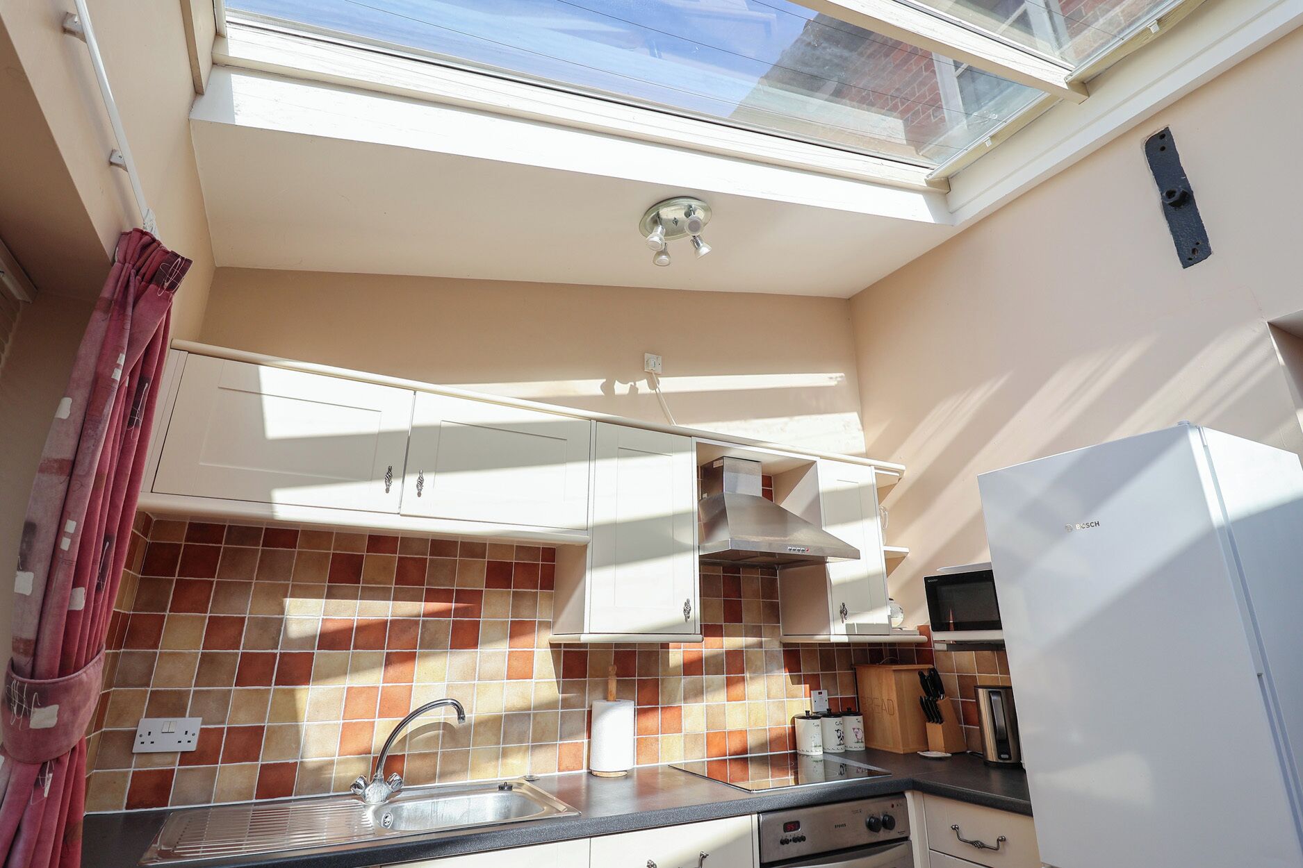 A compact kitchen with a window, a sink, a stove, and cabinets.