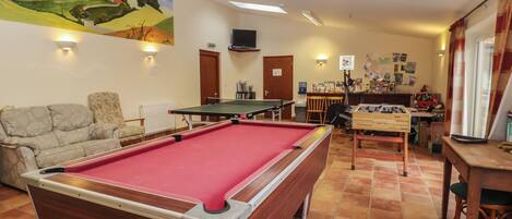 A billiards room with a pool table, a sofa, and a painting on the wall.