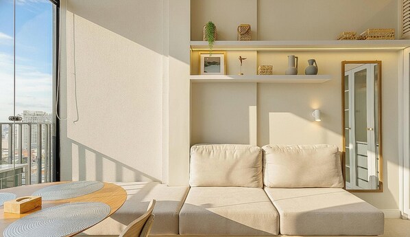 Ein modernes Wohnzimmer mit einer Couch, einem Couchtisch und einem Balkon mit Blick auf die Stadt.