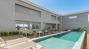 Ein modernes Gebäude mit Schwimmbad, Außenbereich zum Sitzen und Fitnessgeräten.