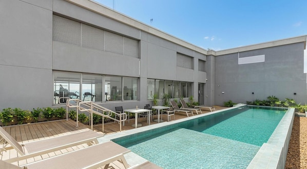 A modern building with a swimming pool, outdoor seating, and exercise equipment. - Aptos modernos em prédio com piscina a 300m do metrô - UOYs (São Paulo)