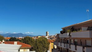 A cityscape with a clear blue sky, a distant mountain range, and a tower.