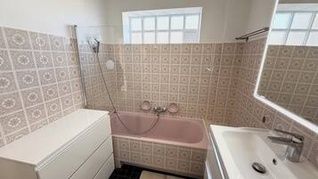 Un baño con bañera, lavamanos y ventana.