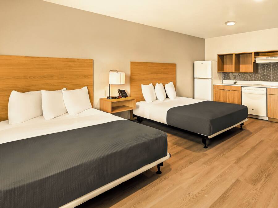 Una habitación de hotel con dos camas, kitchenette y piso de madera.