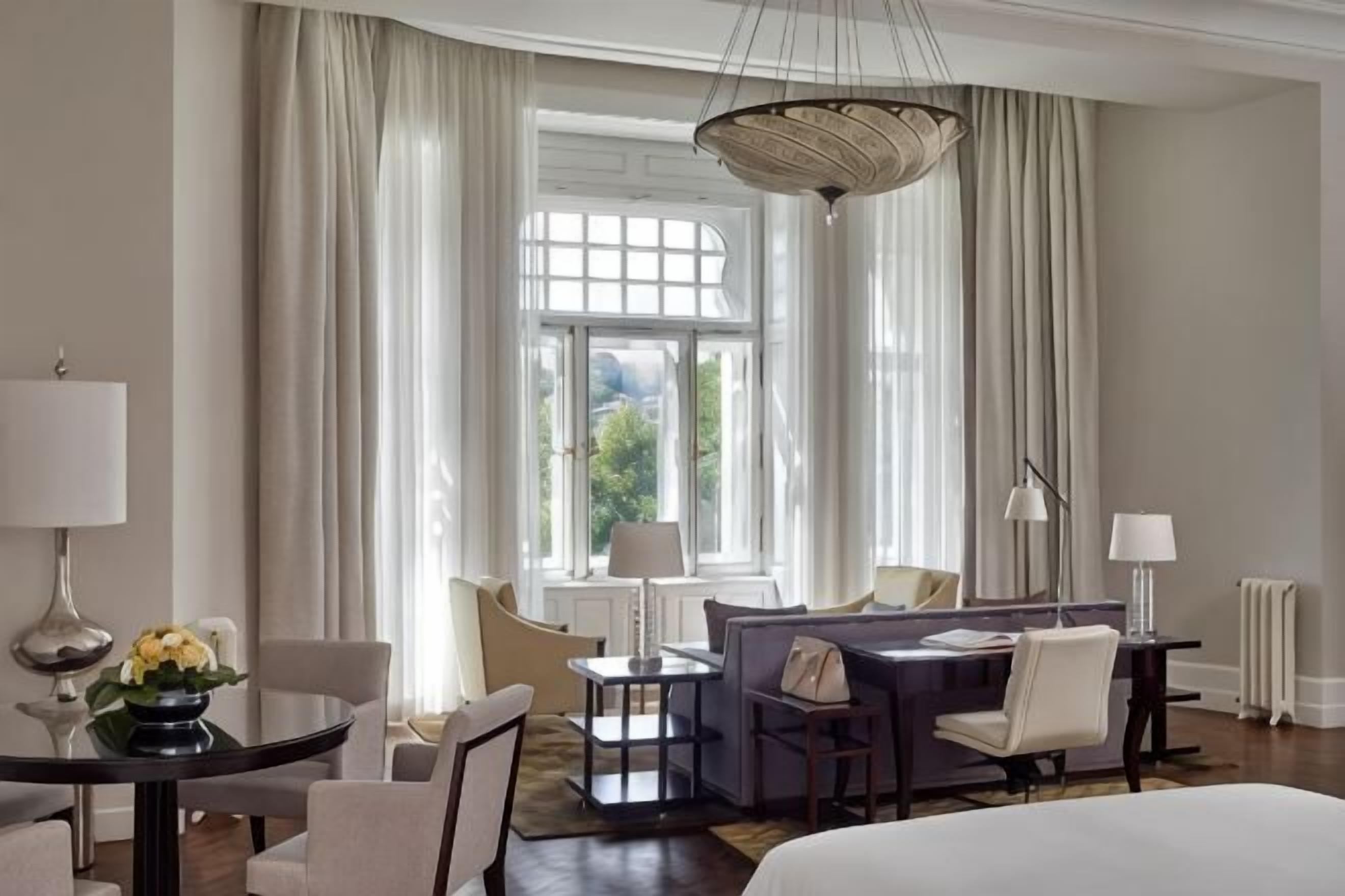 Quarto de hotel com cama, escrivaninha, cadeira, sofá e mesa de jantar.