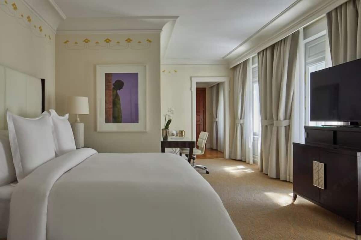 Habitación de hotel con una cama grande, televisor, escritorio con silla y un cuadro en la pared.