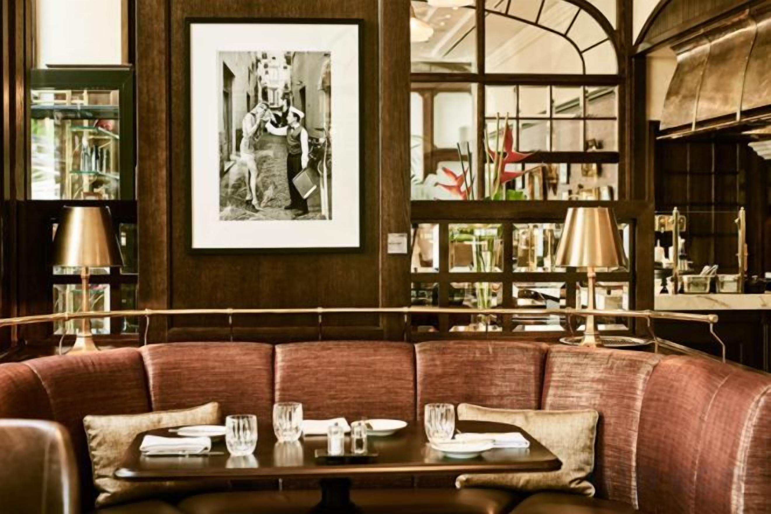 A restaurant with a wooden booth seating area, a framed black and white photograph on the wall, and a bookshelf in the background.