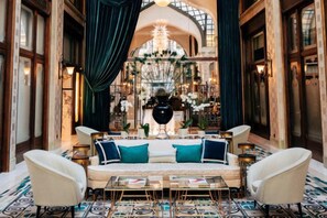 A luxurious interior with a central seating area, ornate chandelier, and a patterned floor.