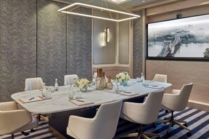 A conference room with a long table, chairs, and a large window with a view of a bridge.