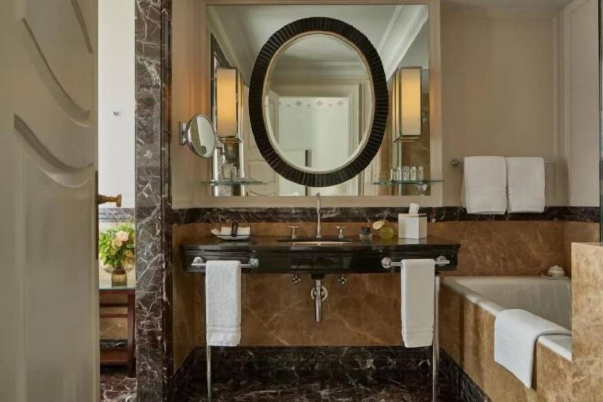 Un baño con lavamanos de mármol, un espejo grande y una bañera.