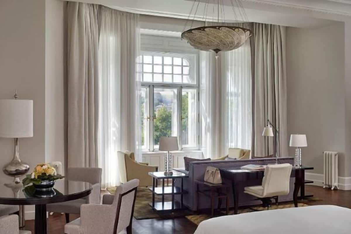 Habitación de hotel con cama, sofá, mesa de comedor y candelabro.