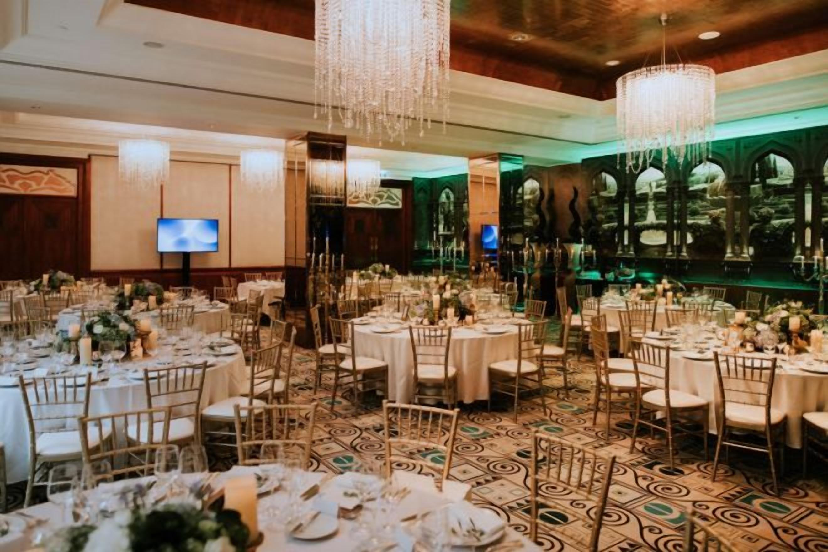 A banquet hall with round tables, chairs, and a chandelier.