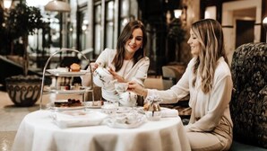 Two people seated at a round table with a white tablecloth, enjoying a tea service. - Four Seasons Hotel Gresham Palace Budapest (Budapest)