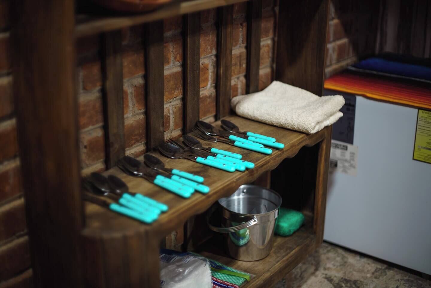 A kitchen shelf with various utensils and a metal pot.