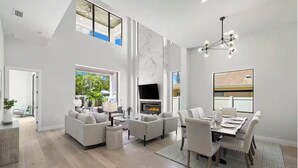 Un salon spacieux doté d’une cheminée, d’un coin repas et d’une grande fenêtre donnant sur l’extérieur.